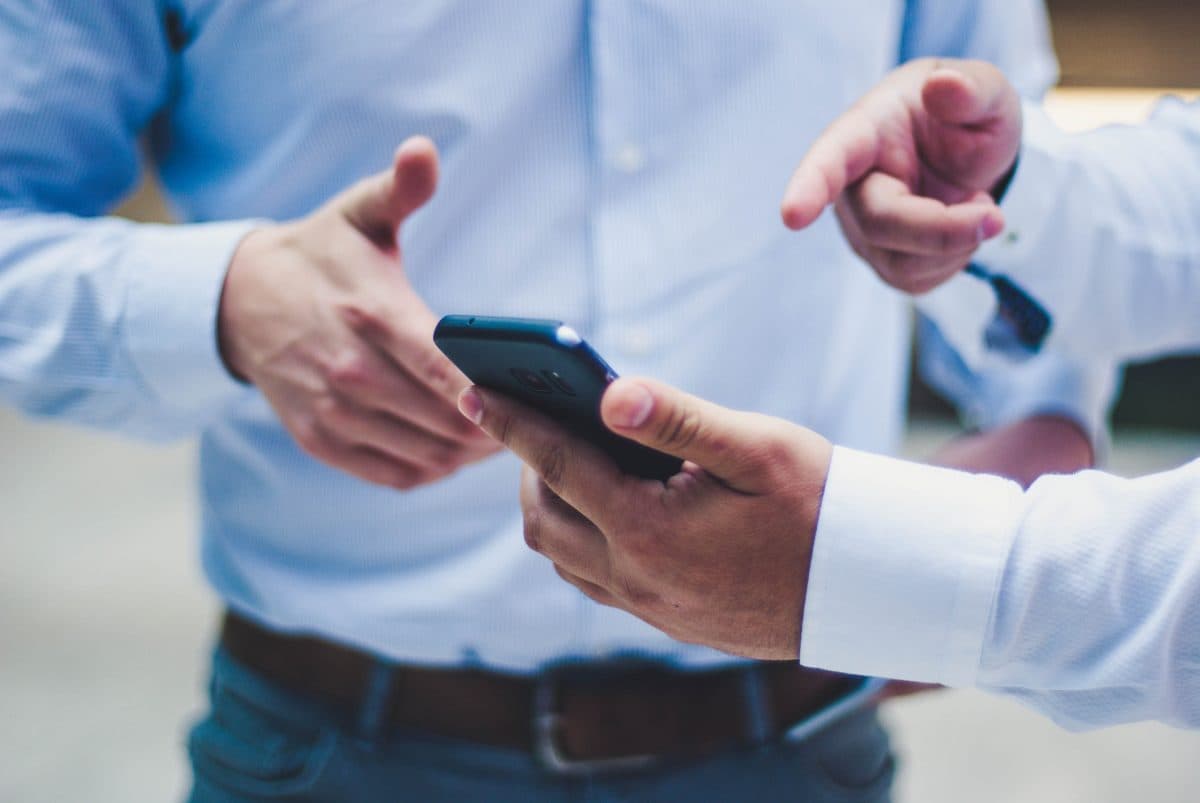 A man is showing something on a mobile phone to another person