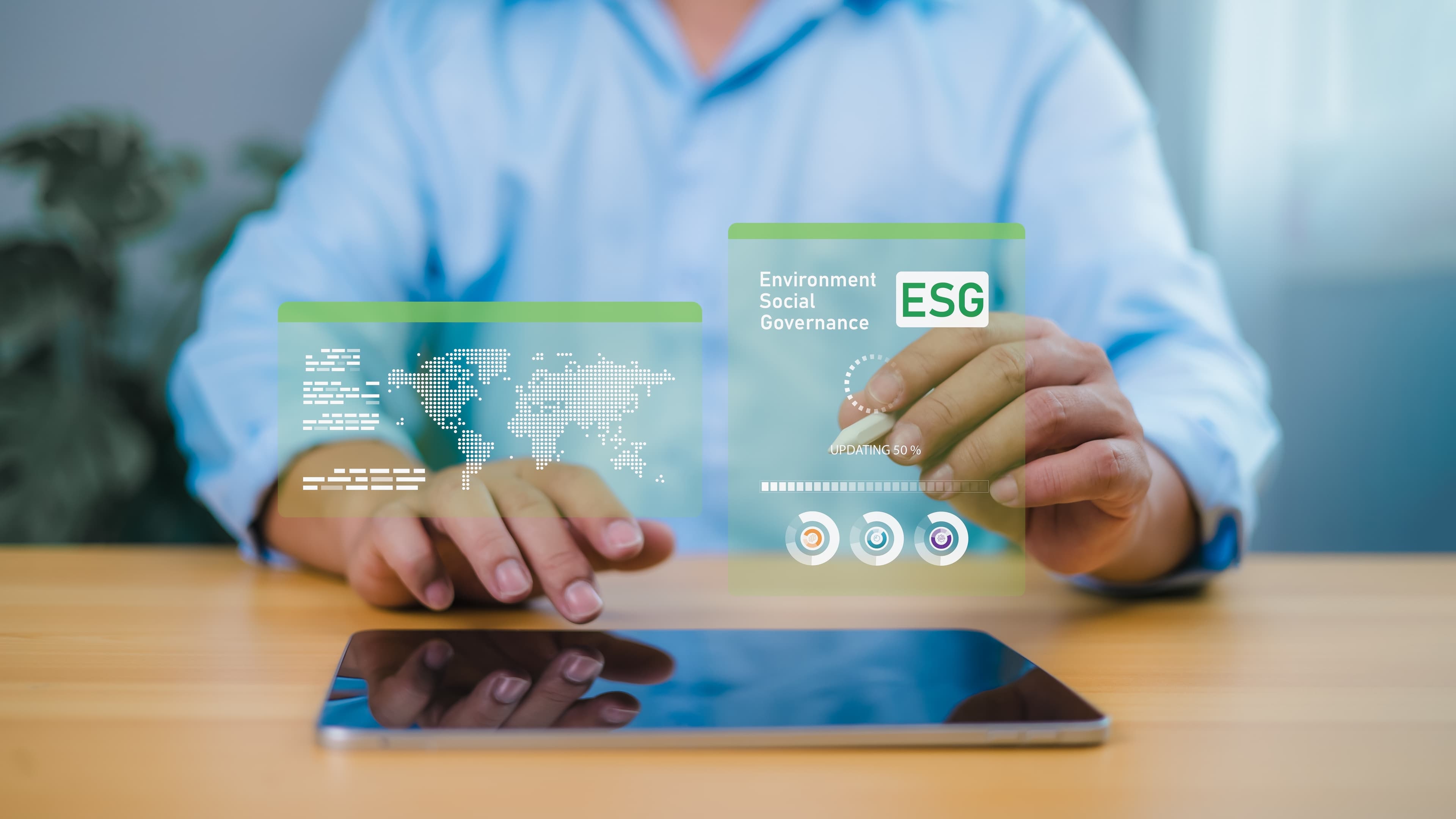 ESG webinar takeaways MENA Man working on a tablet on ESG and compliance reporting. Data related to region and are shown as green visuals in front of him.